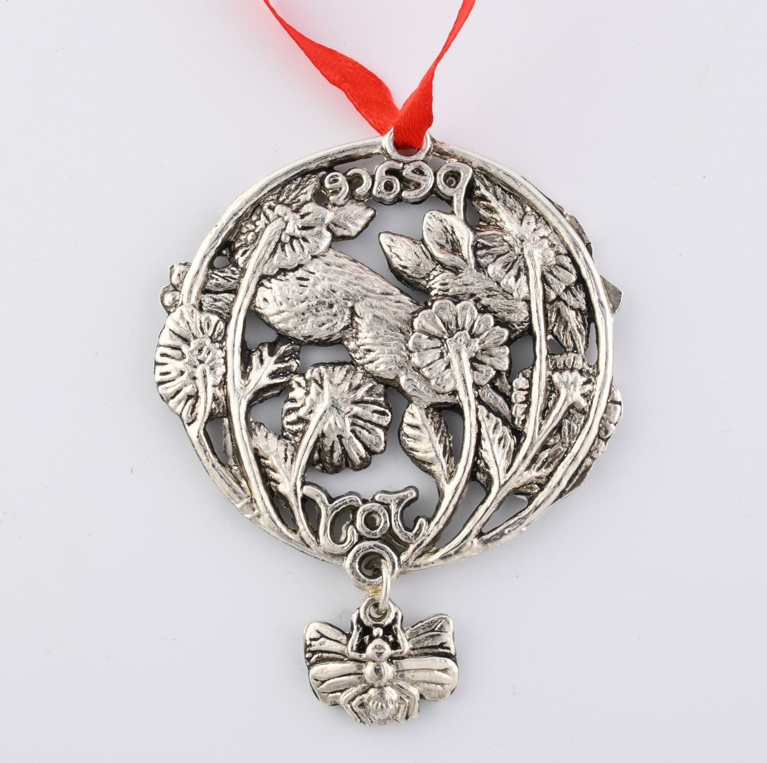 Intricately designed ornament with hare and floral motifs, viewed from above, featuring words "Peace" and "Joy" with a red ribbon.
