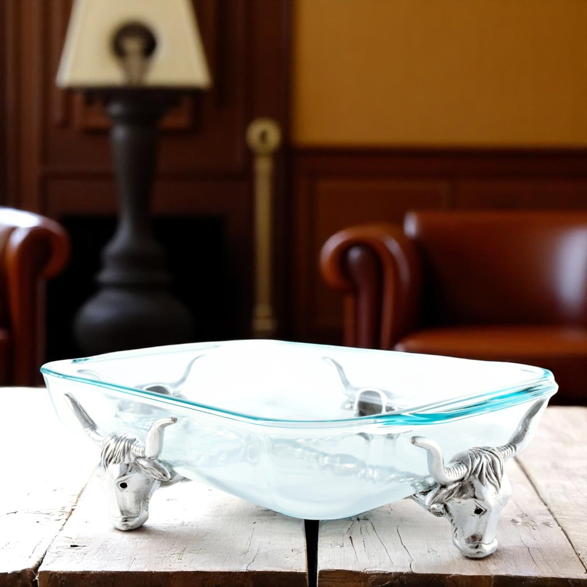 Glass casserole server with bullhead metal accents viewed from an angle, highlighting its artisanal craftsmanship and modern classic design.
