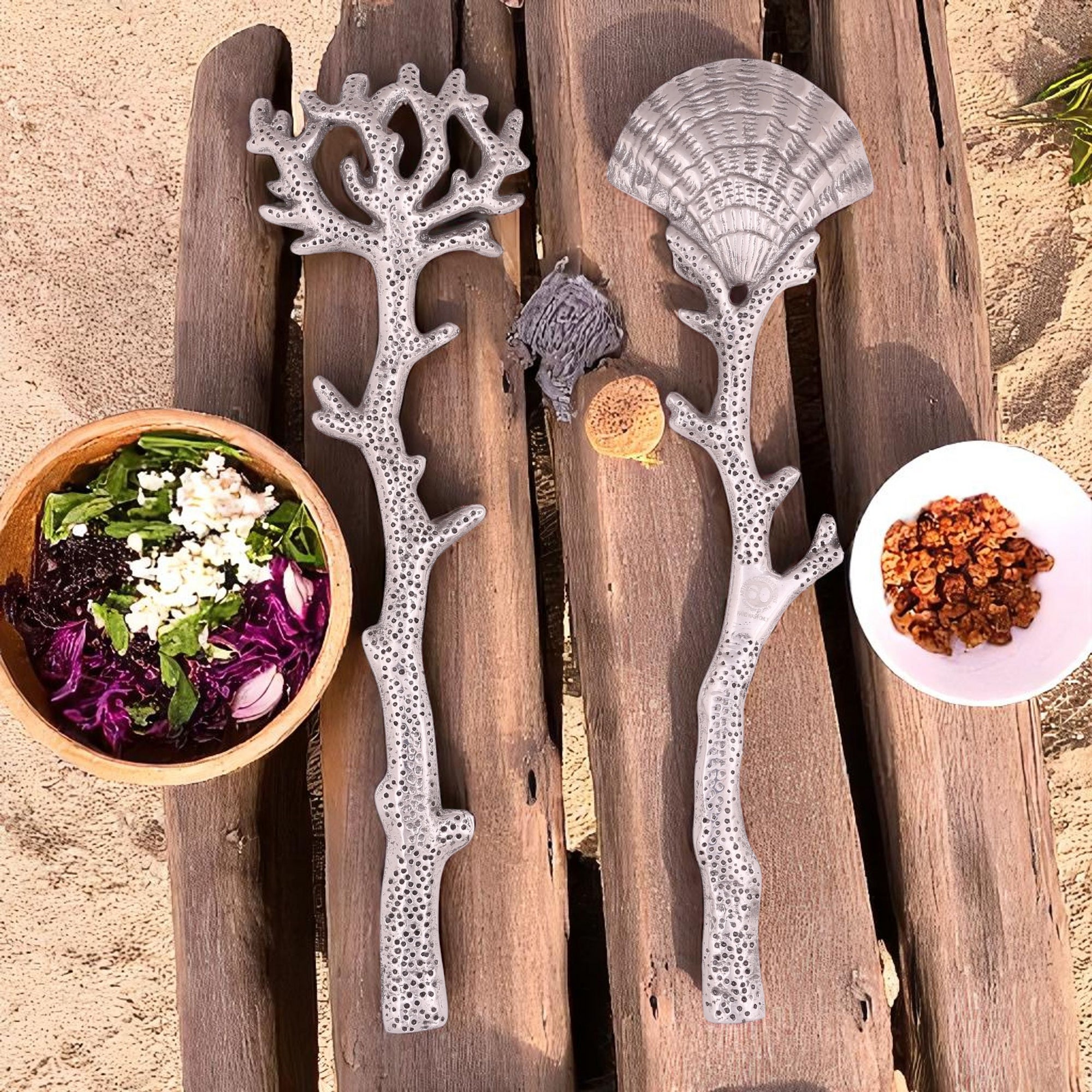 Angled view of an elegant salad serving set with silver coral-inspired handles, showcasing artisanal craftsmanship on a white background.