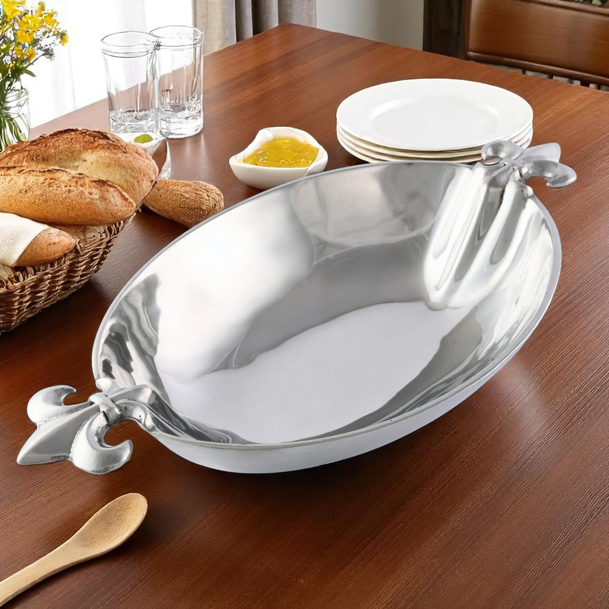 A decorative serving bowl filled with apples and oranges viewed at an angle, showcasing its elegant handles.