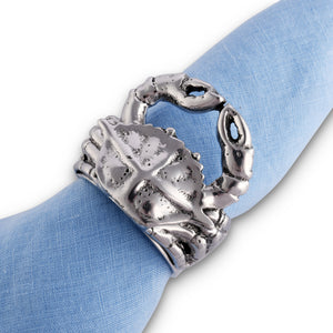 A crab-shaped napkin ring adorns a blue fabric napkin, viewed from above, evoking coastal decor elegance.