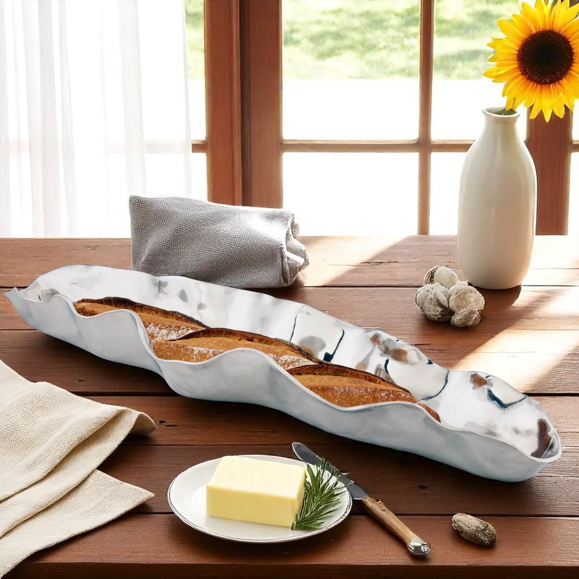 Elegant bread tray with a wavy design holds a baguette, viewed at an angle, showcasing artisanal craftsmanship.