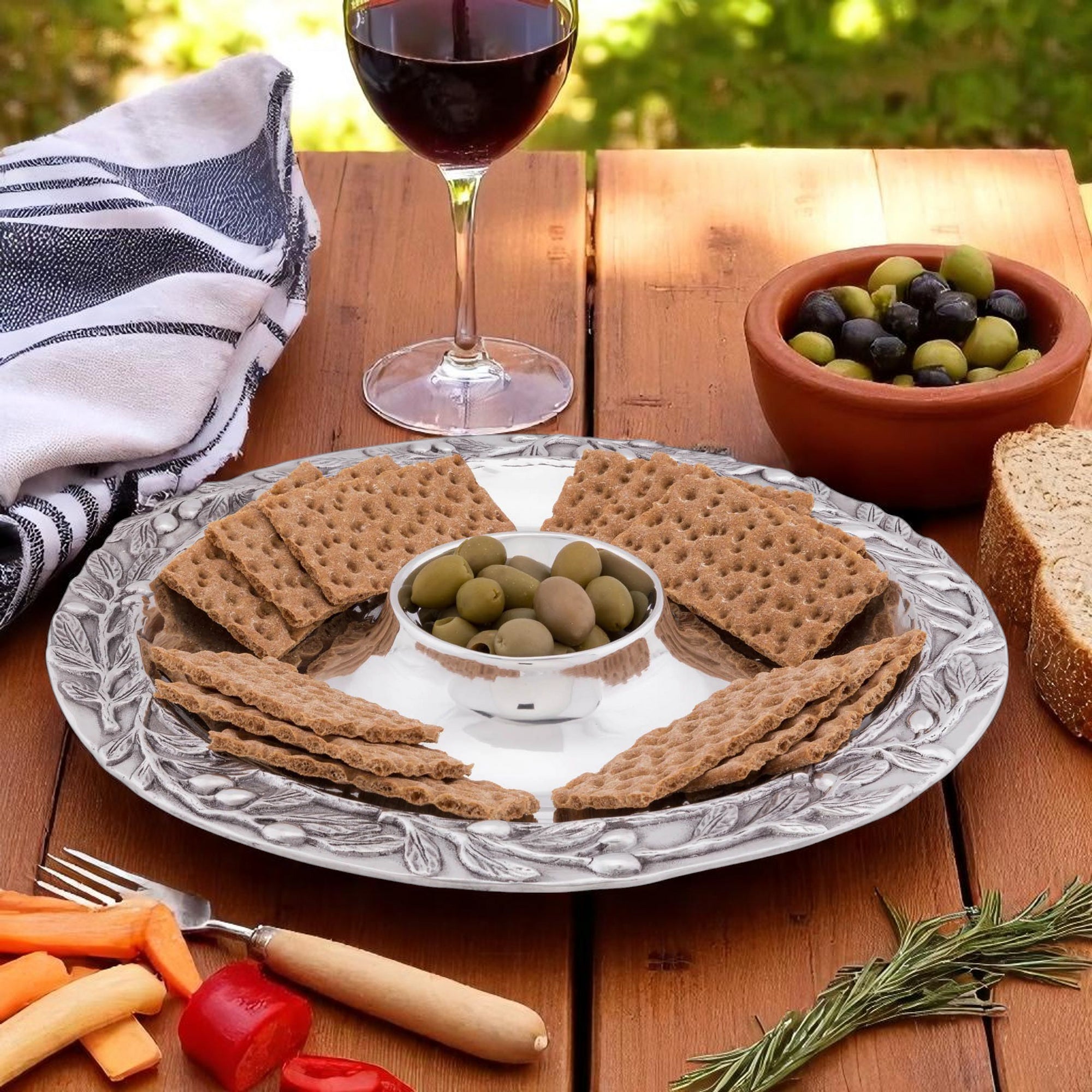 Elegant chip dip set on a textured serving piece, seen at a slight angle, showcasing artisanal craftsmanship with olives and crackers.