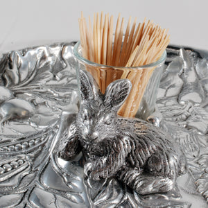 A decorative toothpick holder viewed from a side angle, showcasing a silver rabbit on an intricate serving piece.