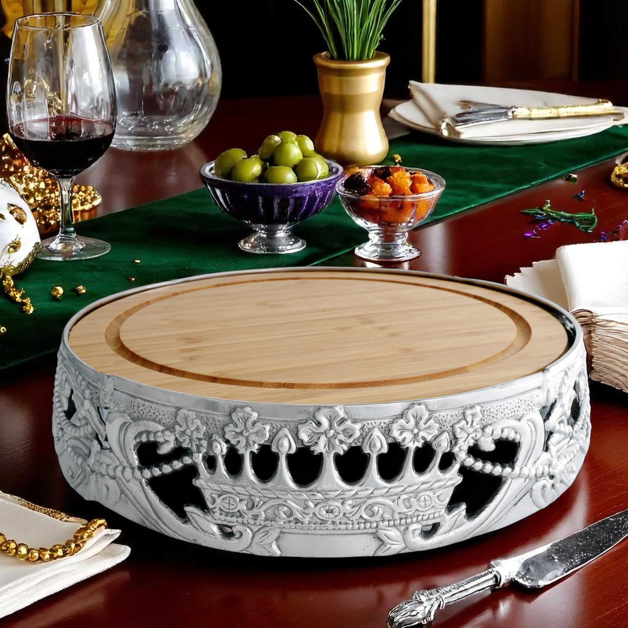 A round cheese board with ornate silver detailing is viewed from a slightly elevated side angle, highlighting its artisanal craftsmanship.