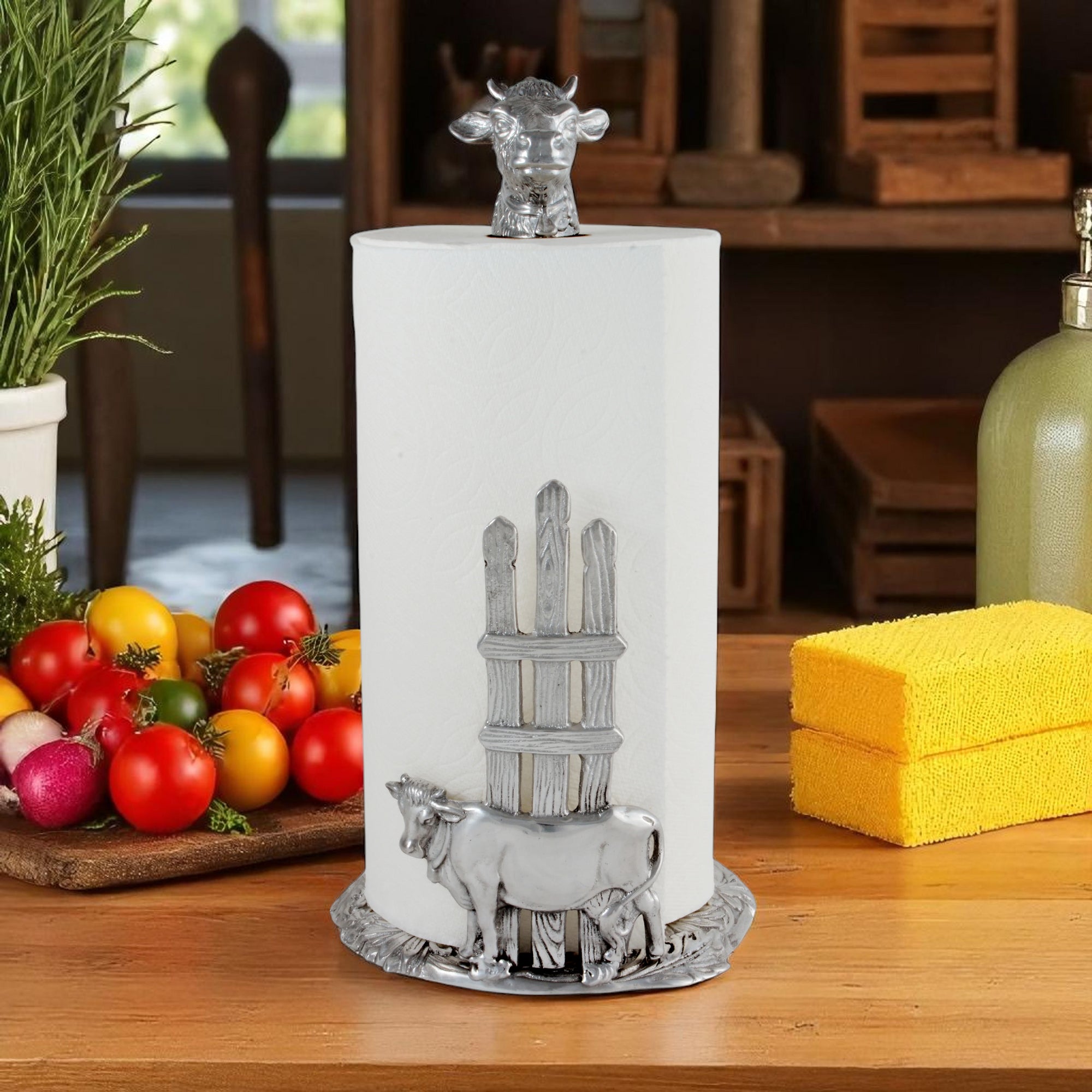 This paper towel holder, viewed from a slight angle, features a cow-themed design on a textured base, adding a rustic touch to kitchen decor.