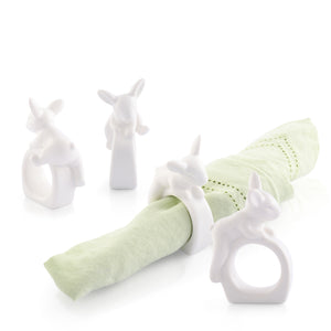 White rabbit-shaped napkin rings elegantly encircle a pale green napkin, viewed from a slightly elevated angle, ideal for a modern classic table setting.