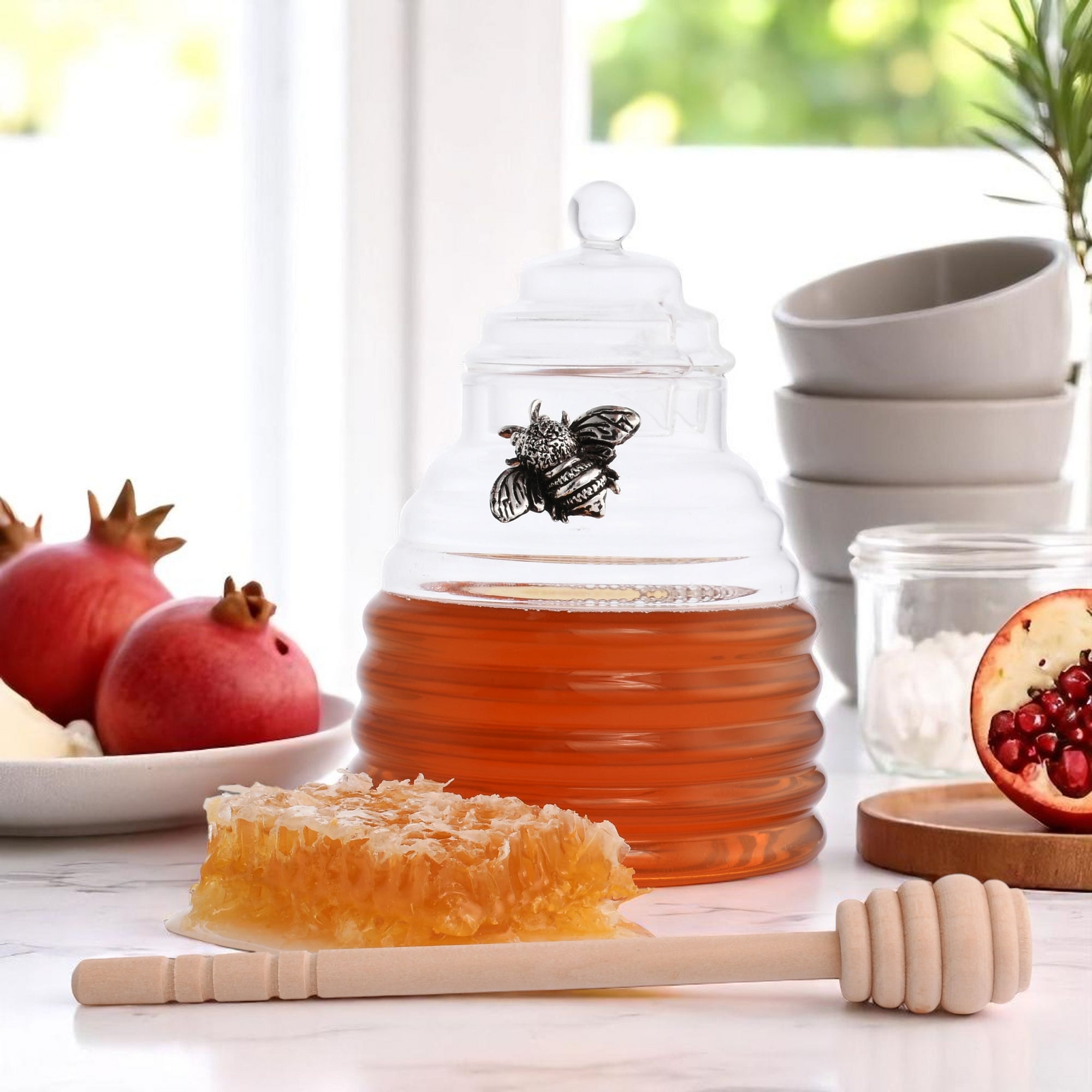Glass honey pot styled from the side, showcasing rich amber honey with a honeycomb and dipper nearby, ideal for kitchen decor.