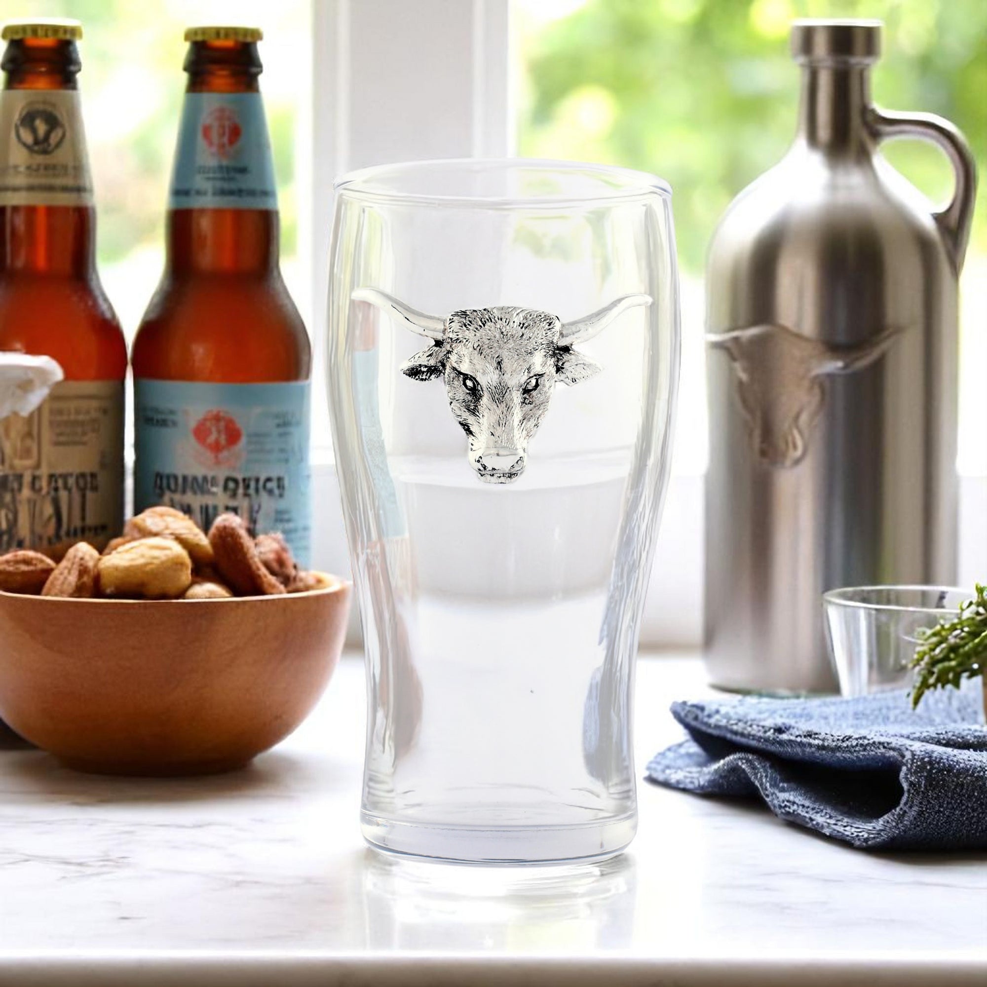 In a side view, a set of four glasses adorned with silver bull heads showcases artisanal craftsmanship, perfect for cocktail accessories.