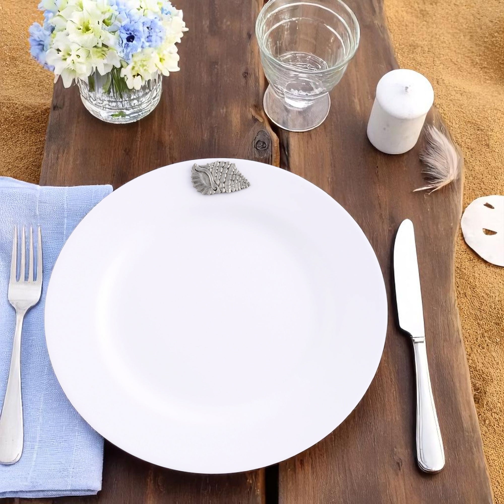 Stacked dinner plates with shell accents seen from a side angle, showcasing coastal decor in elegant tableware.