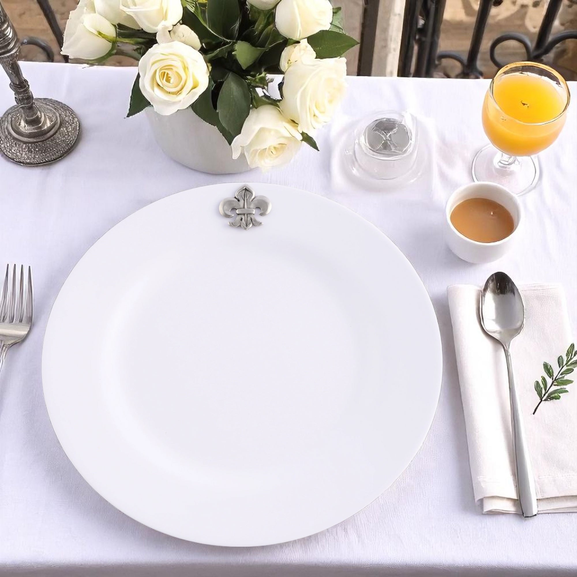 A stack of elegant dinner plates with decorative fleur-de-lis detailing, viewed from the side for a modern classic table setting.