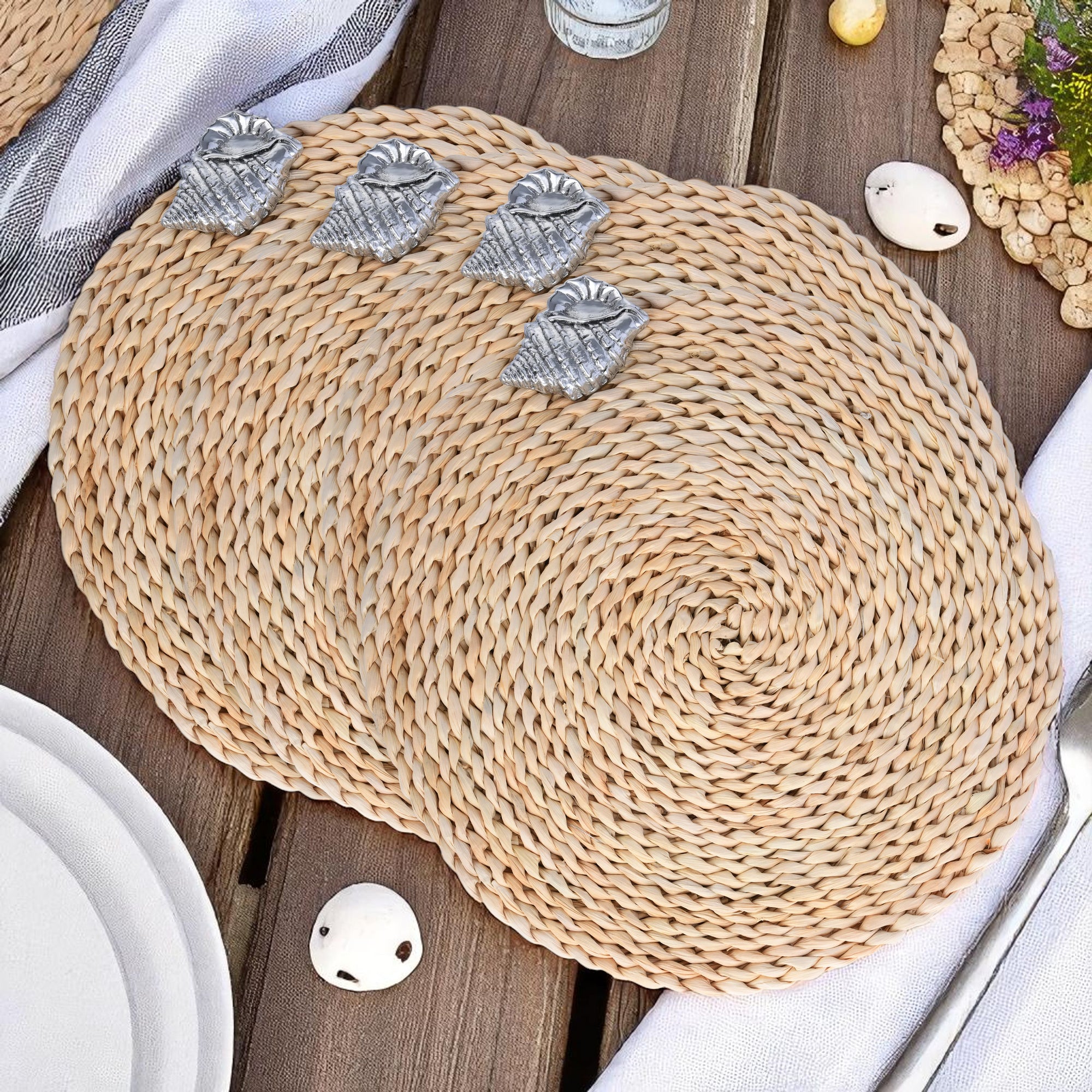 Seen from above, round woven placemats with silver shell accents create an elegant coastal decor for table settings.