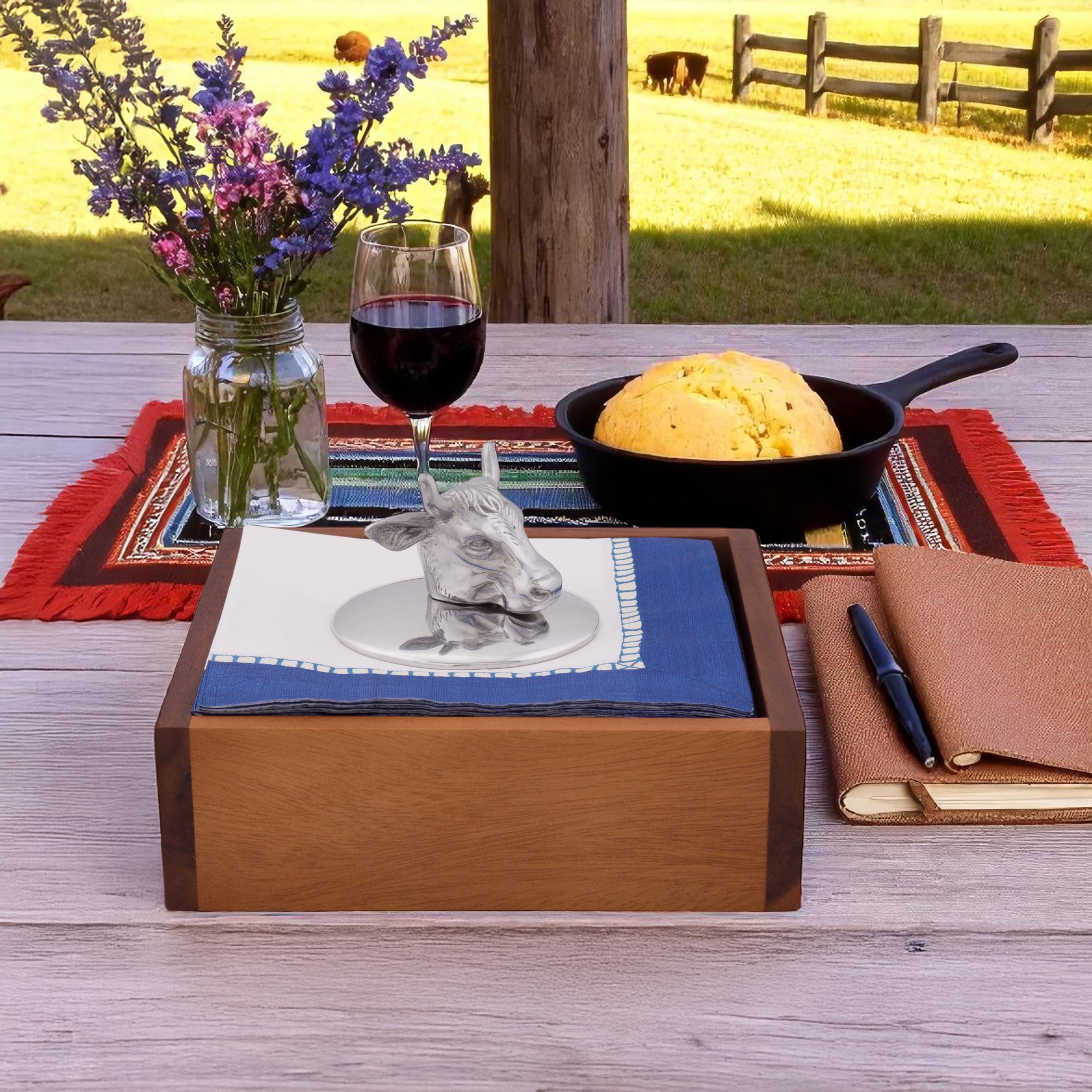 A silver cow napkin weight sits on a stack of blue and white napkins viewed from the side, adding charm to table settings.