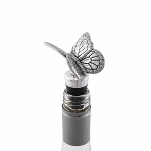 A silver butterfly bottle stopper is seen from a side angle, showcasing its artisanal craftsmanship and elegant accent.
