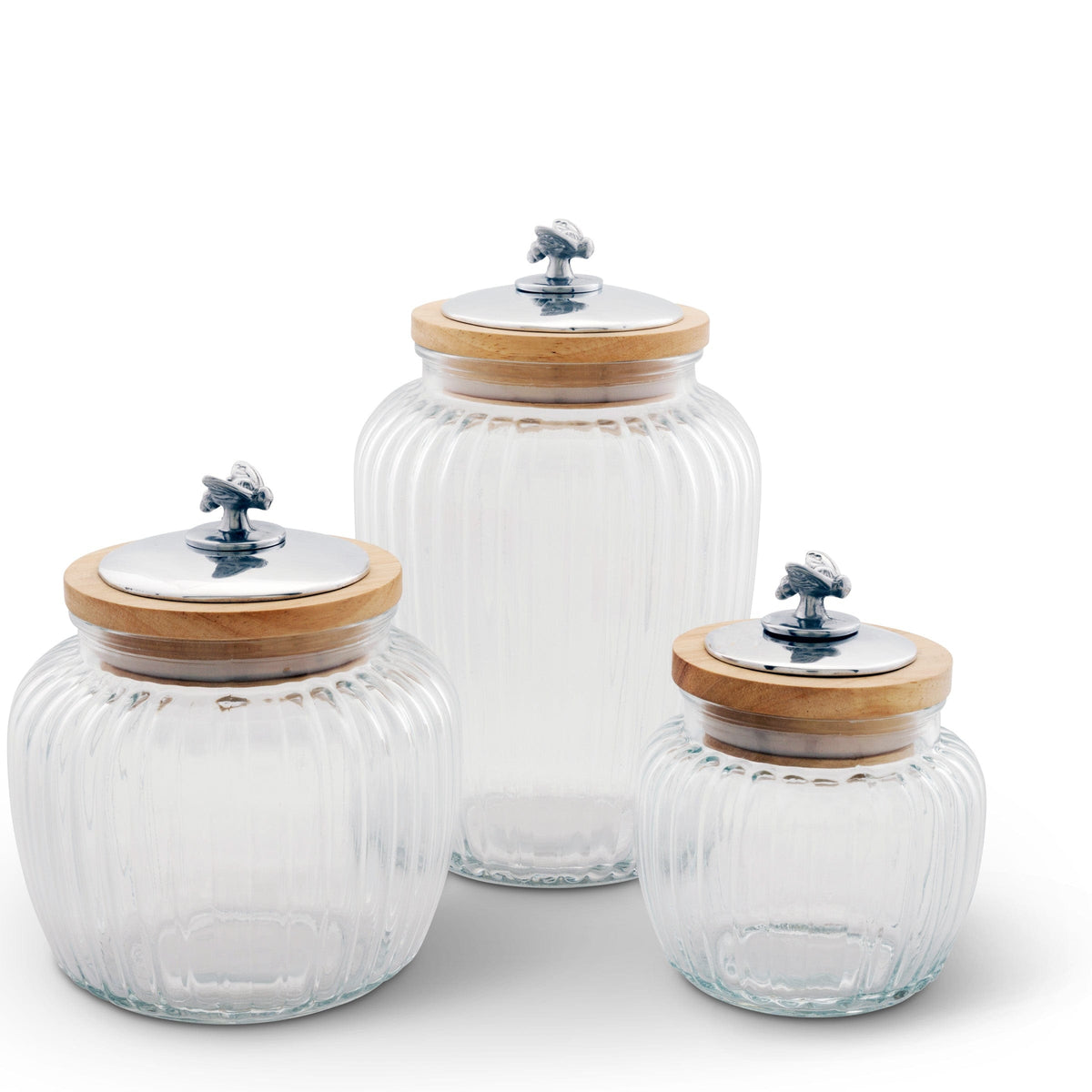 Three glass canisters with decorative metal lids and wooden accents viewed in a slightly angled shot, showcasing elegance in kitchen decor.