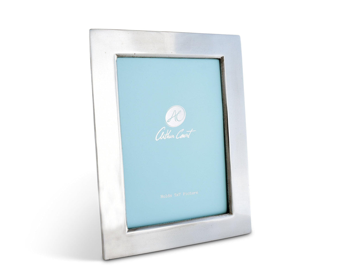 A sleek photo frame with a silver finish is viewed from a slight angle, showcasing its modern classic design against a white background.
