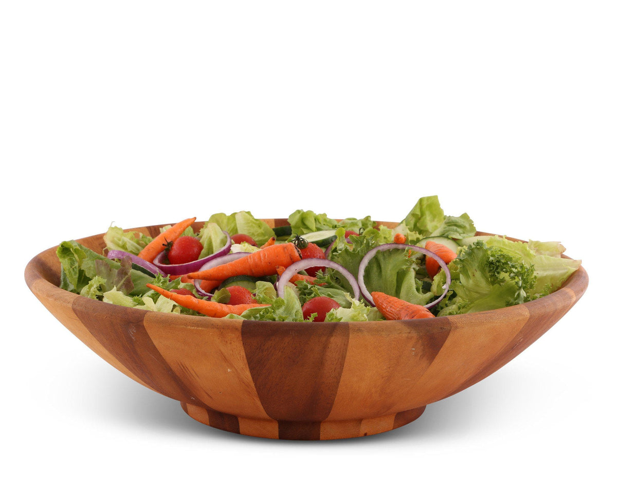 A wooden salad bowl filled with fresh vegetables, including carrots and tomatoes, angled to emphasize its artisanal craftsmanship.